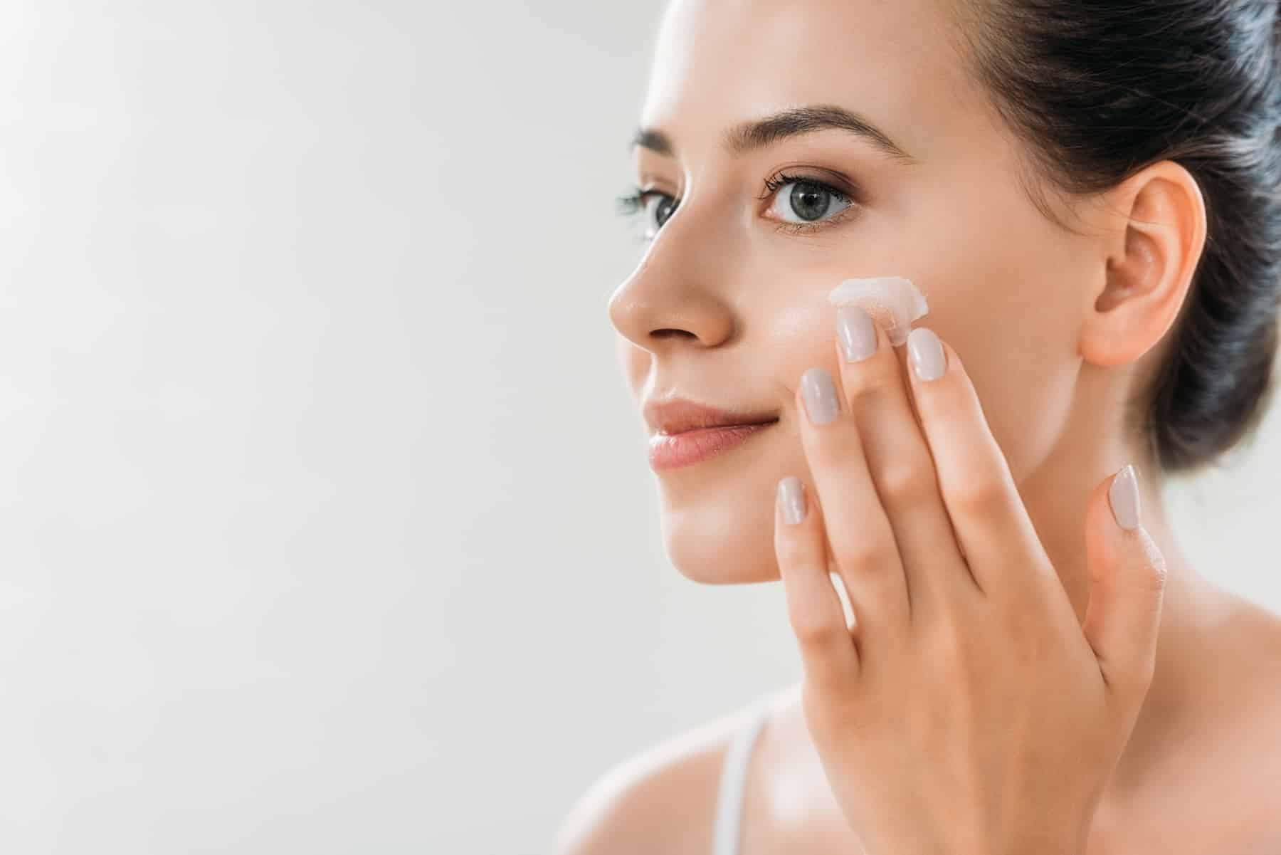 woman applying skincare to her face