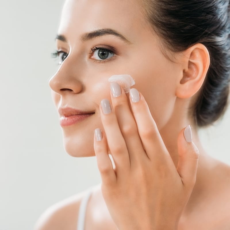 woman applying skincare to her face